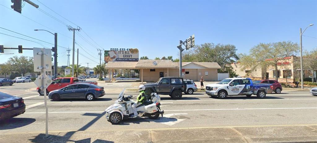 A street-level view shows a commercial building with a billboard and traffic at an intersection — 100 N RIDGEWOOD AVENUE, DAYTONA BEACH, FL