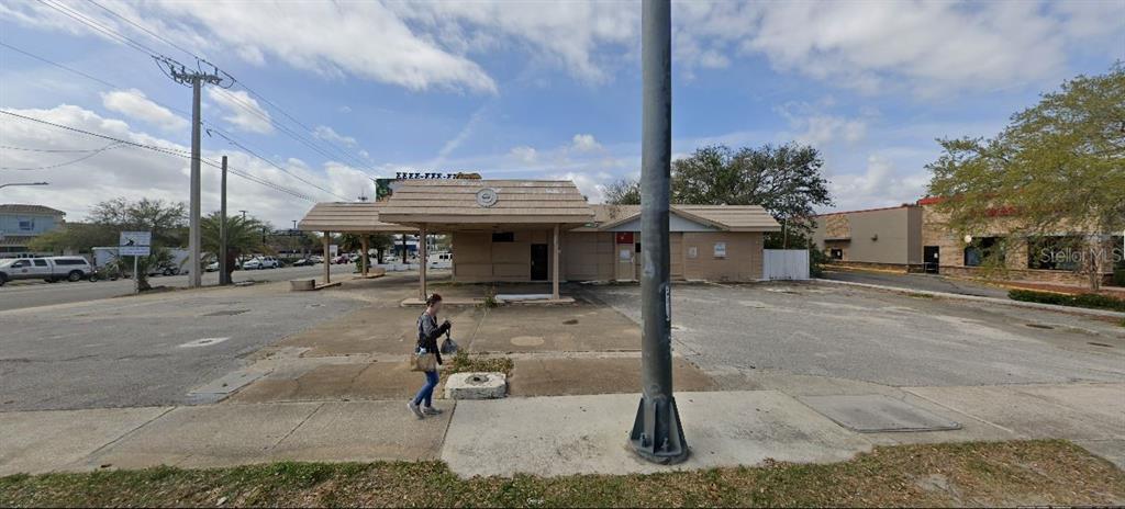 An exterior view of a vacant, single-story commercial building with a large paved parking lot — 100 N RIDGEWOOD AVENUE, DAYTONA BEACH, FL