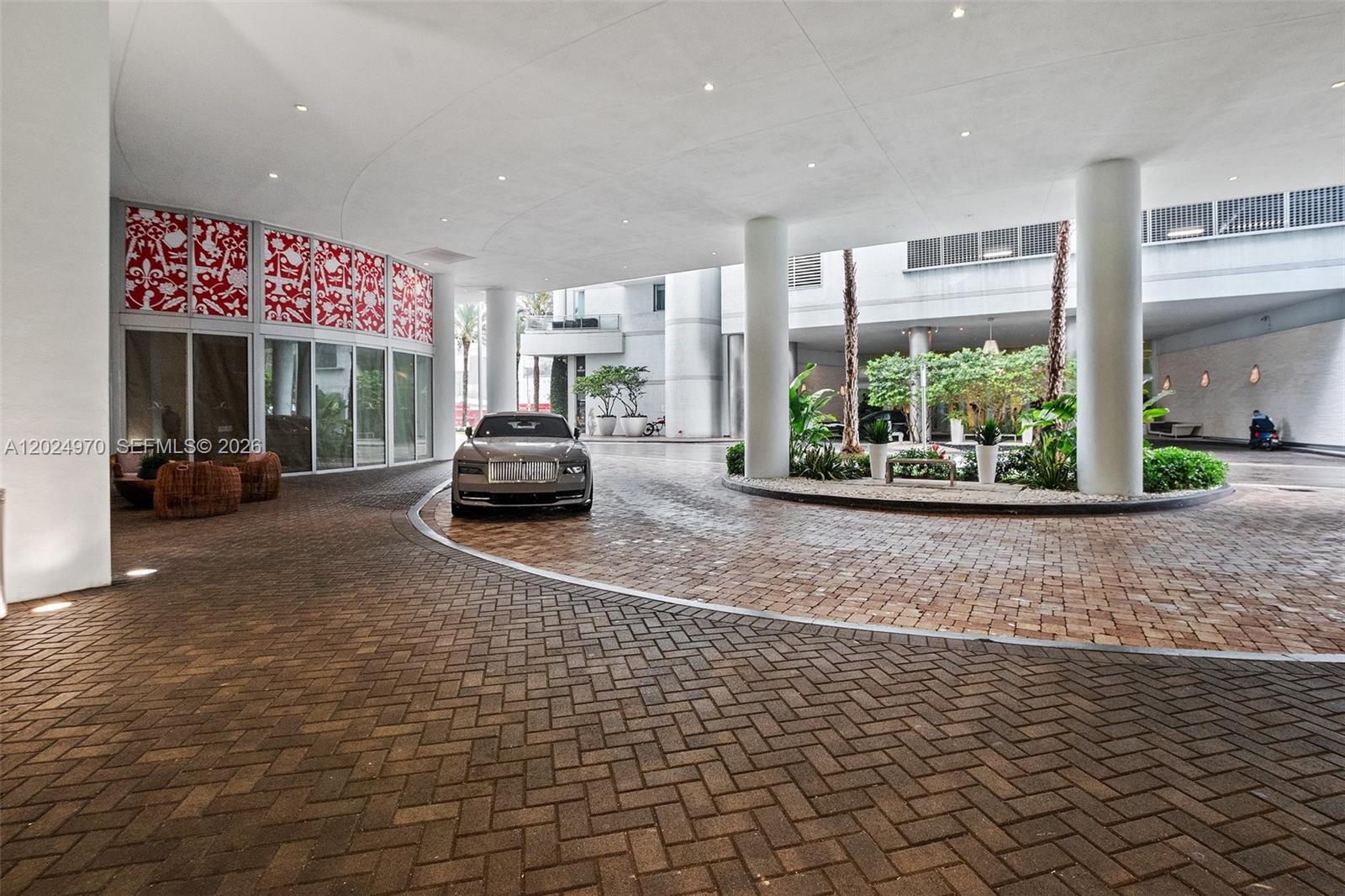 A luxury car is parked under the covered entrance of a modern building with brick paving — 90 SW 3rd St # 3810, Miami FL 33130, MIAMI, FL