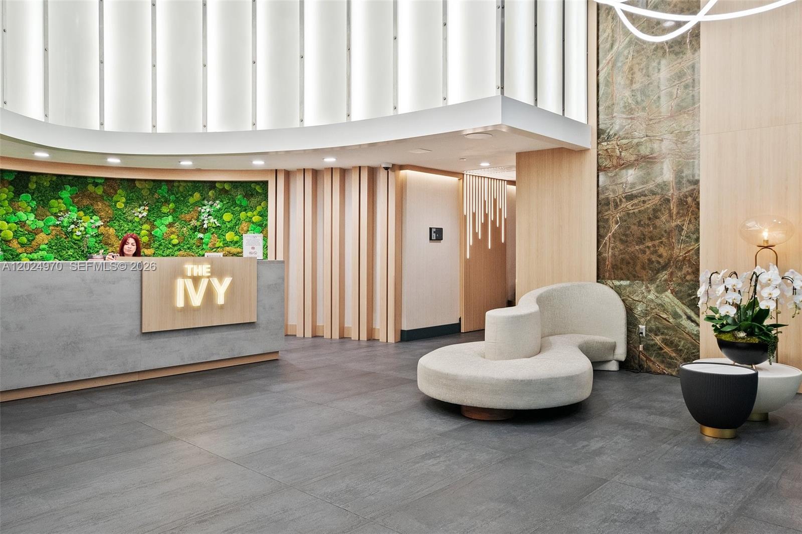 A modern lobby features a reception desk with a moss wall and curved seating — 90 SW 3rd St # 3810, Miami FL 33130, MIAMI, FL