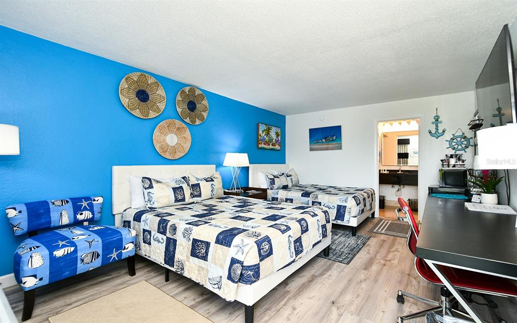 A hotel room features two beds, a blue accent wall, and a desk area — 7150 N TAMIAMI TRAIL UNIT S-614, SARASOTA, FL