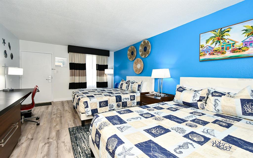 A hotel room features two beds, a desk, and a bright blue accent wall — 7150 N TAMIAMI TRAIL UNIT S-614, SARASOTA, FL