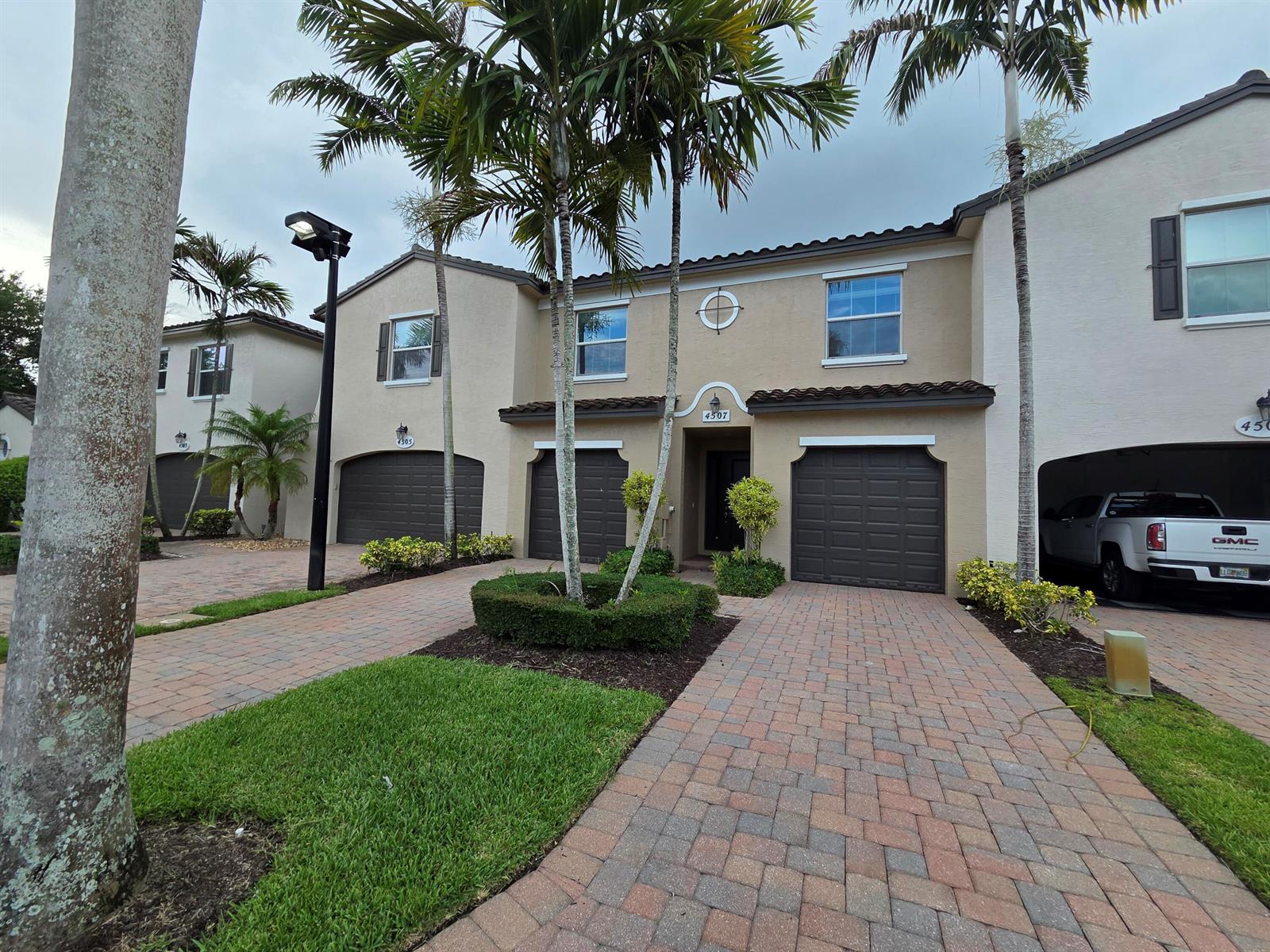 A two-story townhouse exterior features a paved driveway, a garage, and palm trees — 4507 Mediterranean Circle, West Palm Beach FL 33418, WEST PALM BEACH, FL
