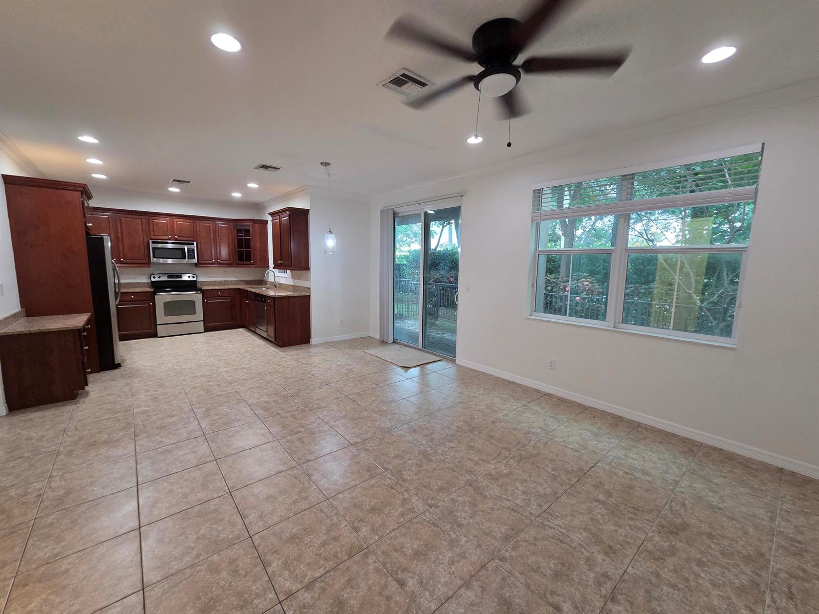 An open-concept kitchen and dining area features dark wood cabinets, tile flooring, and sliding doors — 4507 Mediterranean Circle, West Palm Beach FL 33418, WEST PALM BEACH, FL