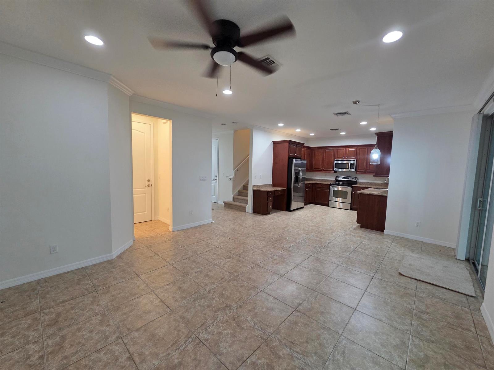 An open-concept living area features tile flooring, a ceiling fan, and a wood-cabinet kitchen — 4507 Mediterranean Circle, West Palm Beach FL 33418, WEST PALM BEACH, FL