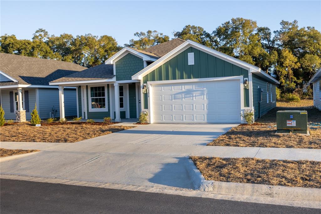 A green single-story house with a white garage door and a concrete driveway — 25039 SW 250TH PLACE, NEWBERRY, FL