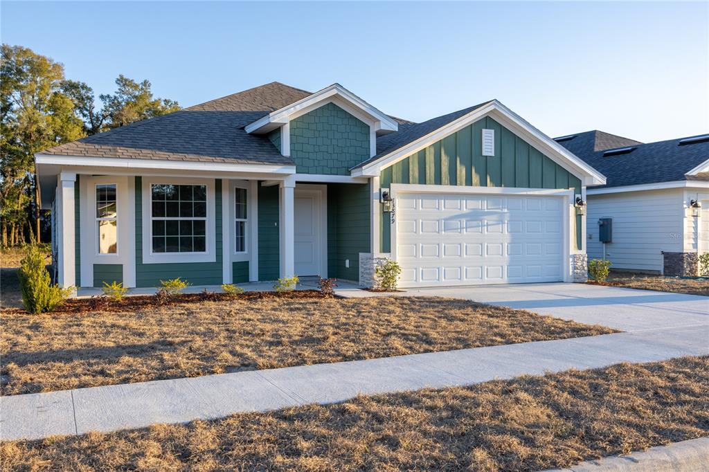 A green, single-story suburban house with a two-car garage and a concrete driveway — 25039 SW 250TH PLACE, NEWBERRY, FL