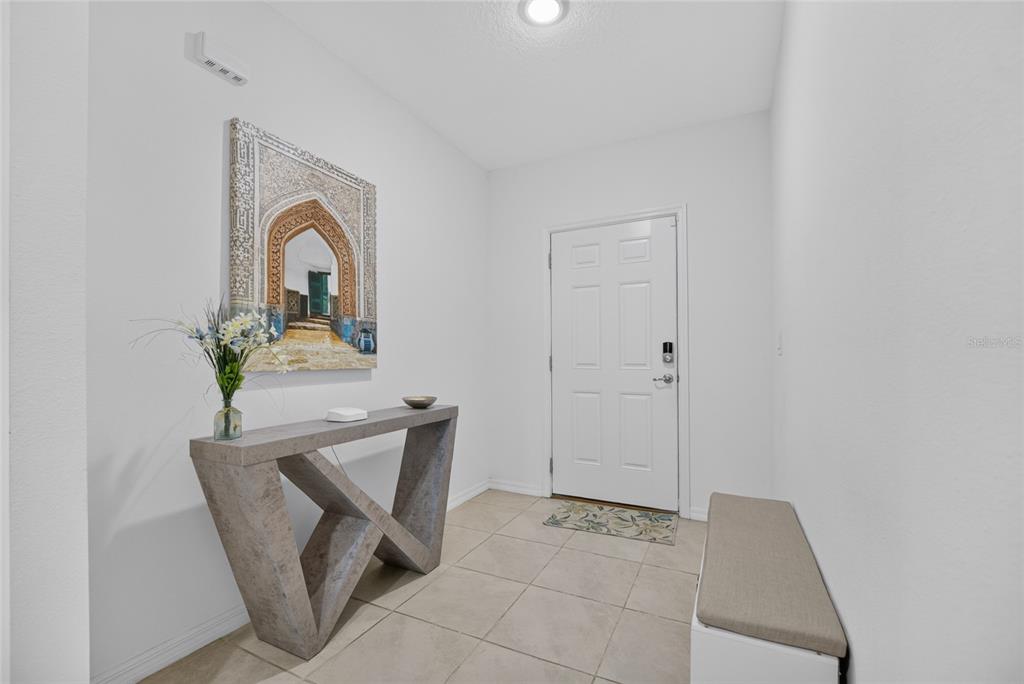 An entryway features a console table, a wall painting, a bench, and tile flooring — 15685 SW 40TH AVENUE, OCALA, FL