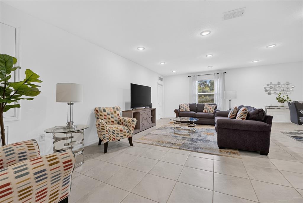 A living room features tile flooring, a television on a console, and patterned armchairs — 15685 SW 40TH AVENUE, OCALA, FL