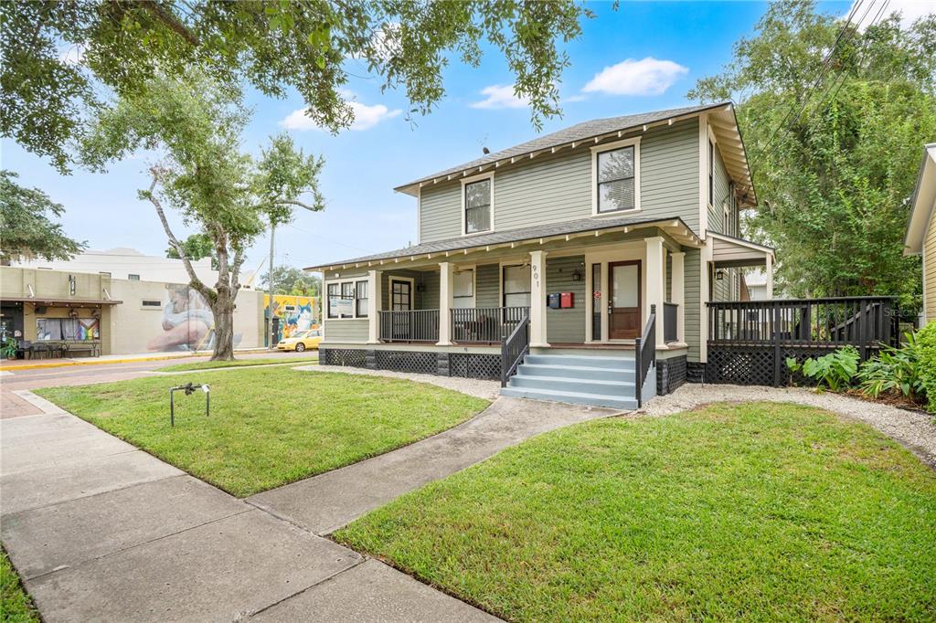 A two-story green house with a front porch and stairs sits on a grassy lot — 901 E WASHINGTON STREET, ORLANDO, FL