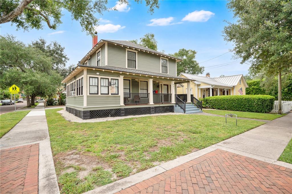 A two-story green house with a front porch sits on a corner lot with sidewalks — 901 E WASHINGTON STREET, ORLANDO, FL