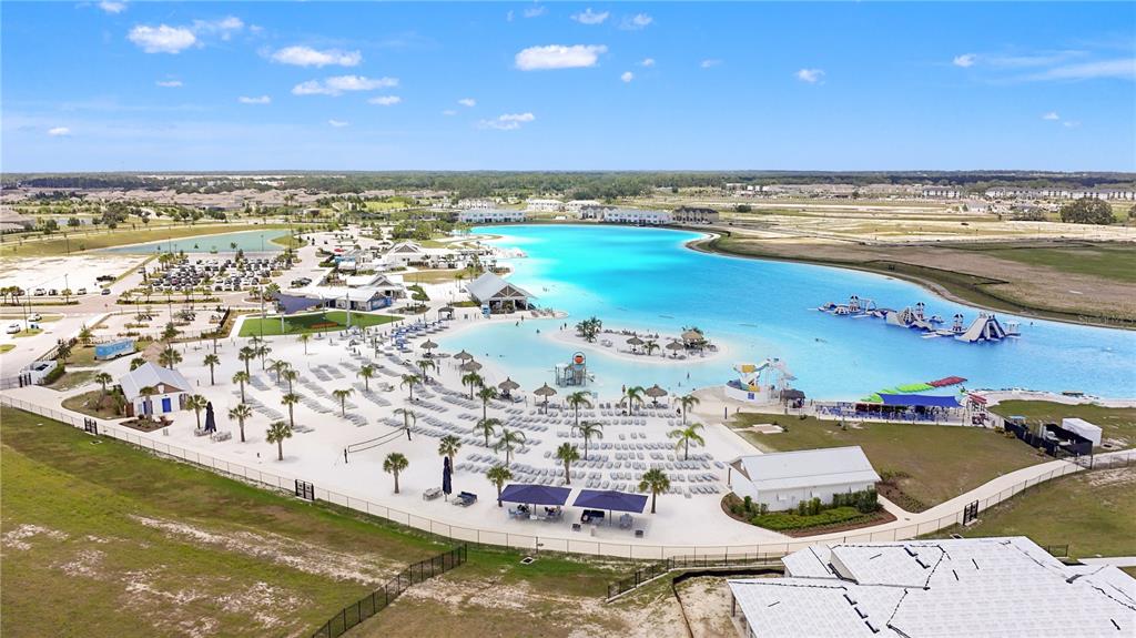 An aerial view shows a large man-made turquoise lagoon with sandy beaches and water slides — 32235 POWDERPUFF MIMOSA DRIVE, SAN ANTONIO, FL