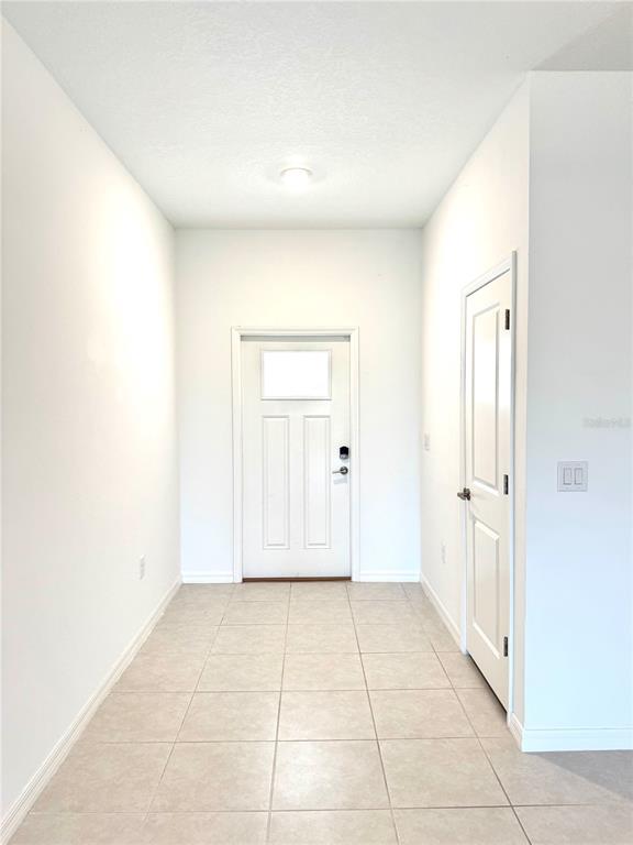 An entryway features light-colored tile flooring, white walls, a front door, and a side door — 32235 POWDERPUFF MIMOSA DRIVE, SAN ANTONIO, FL