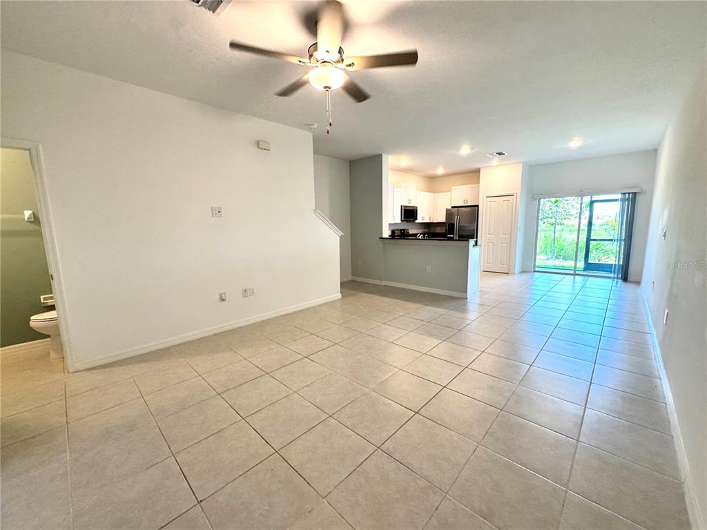 An open-concept living area with tile flooring, a ceiling fan, and an adjacent kitchen — 32235 POWDERPUFF MIMOSA DRIVE, SAN ANTONIO, FL