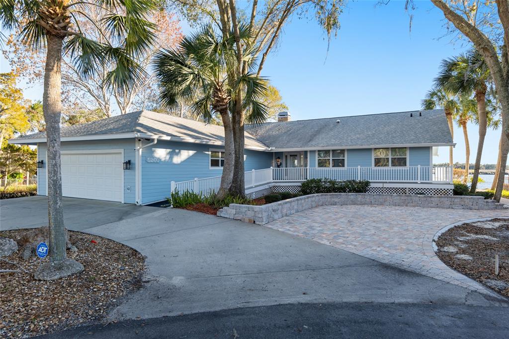 A light blue single-story house features a white garage, a paved driveway, and a porch — 5260 S MYSTIC POINT, HOMOSASSA, FL