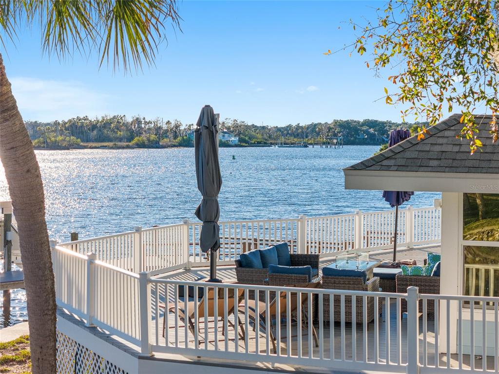 A deck with outdoor furniture overlooks a body of water with a distant shoreline — 5260 S MYSTIC POINT, HOMOSASSA, FL