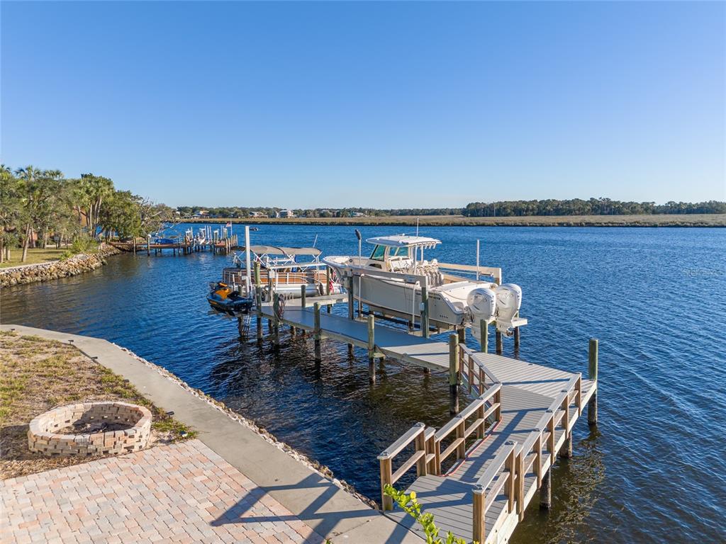 A boat dock with a boat and jet ski extends into a calm river — 5260 S MYSTIC POINT, HOMOSASSA, FL