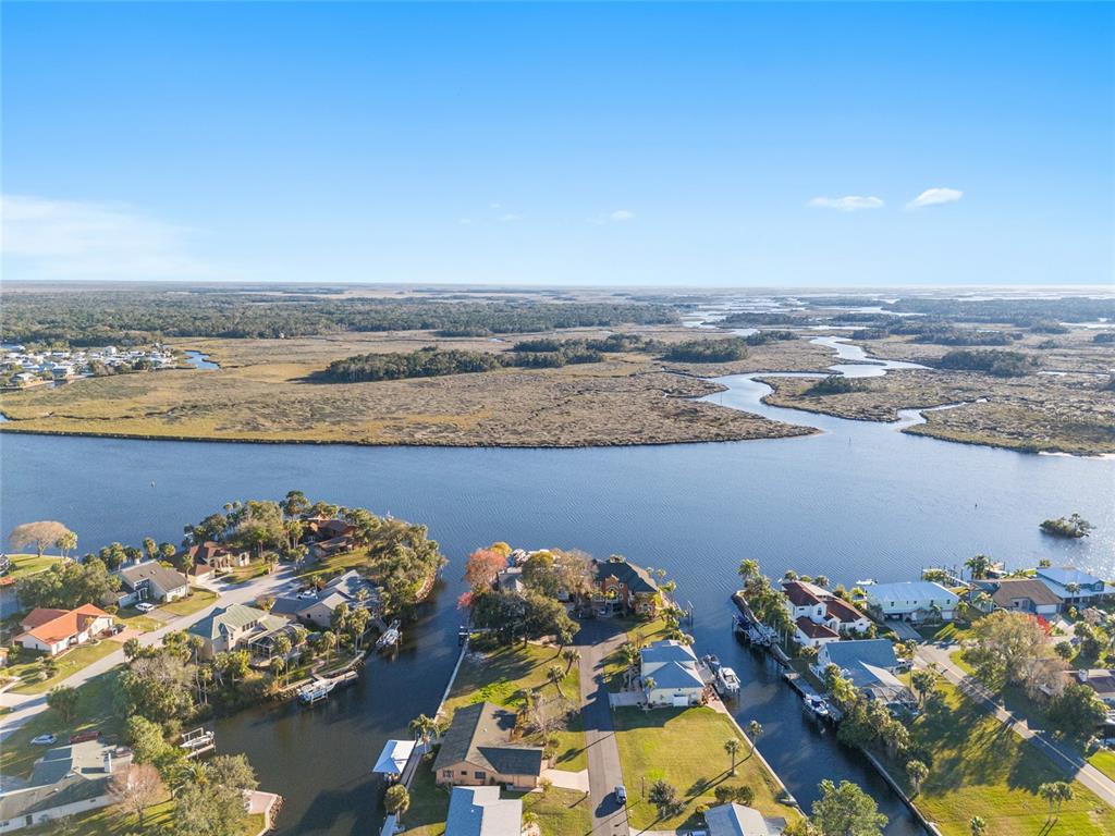 An aerial view shows waterfront houses along canals leading to a large marshy river — 5260 S MYSTIC POINT, HOMOSASSA, FL