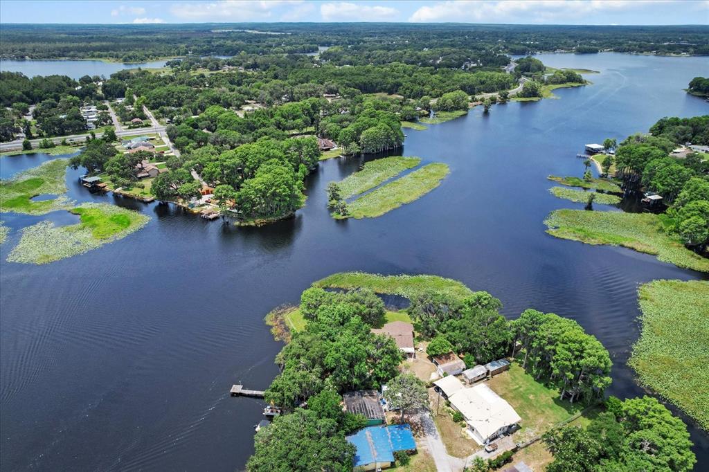 An aerial view shows a waterfront property with houses, docks, and trees surrounded by water — 1226 S TELEPHONE POINT ROAD, INVERNESS, FL
