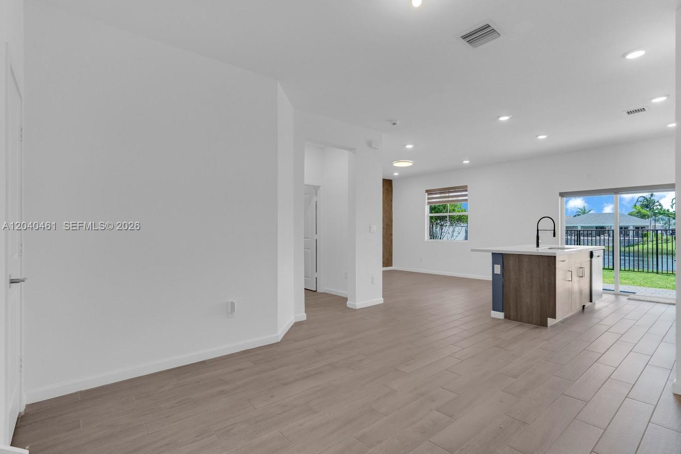 An open-concept kitchen and living area features light wood-look tile flooring and a center island — 805 SE 18th St, Homestead FL 33034, HOMESTEAD, FL