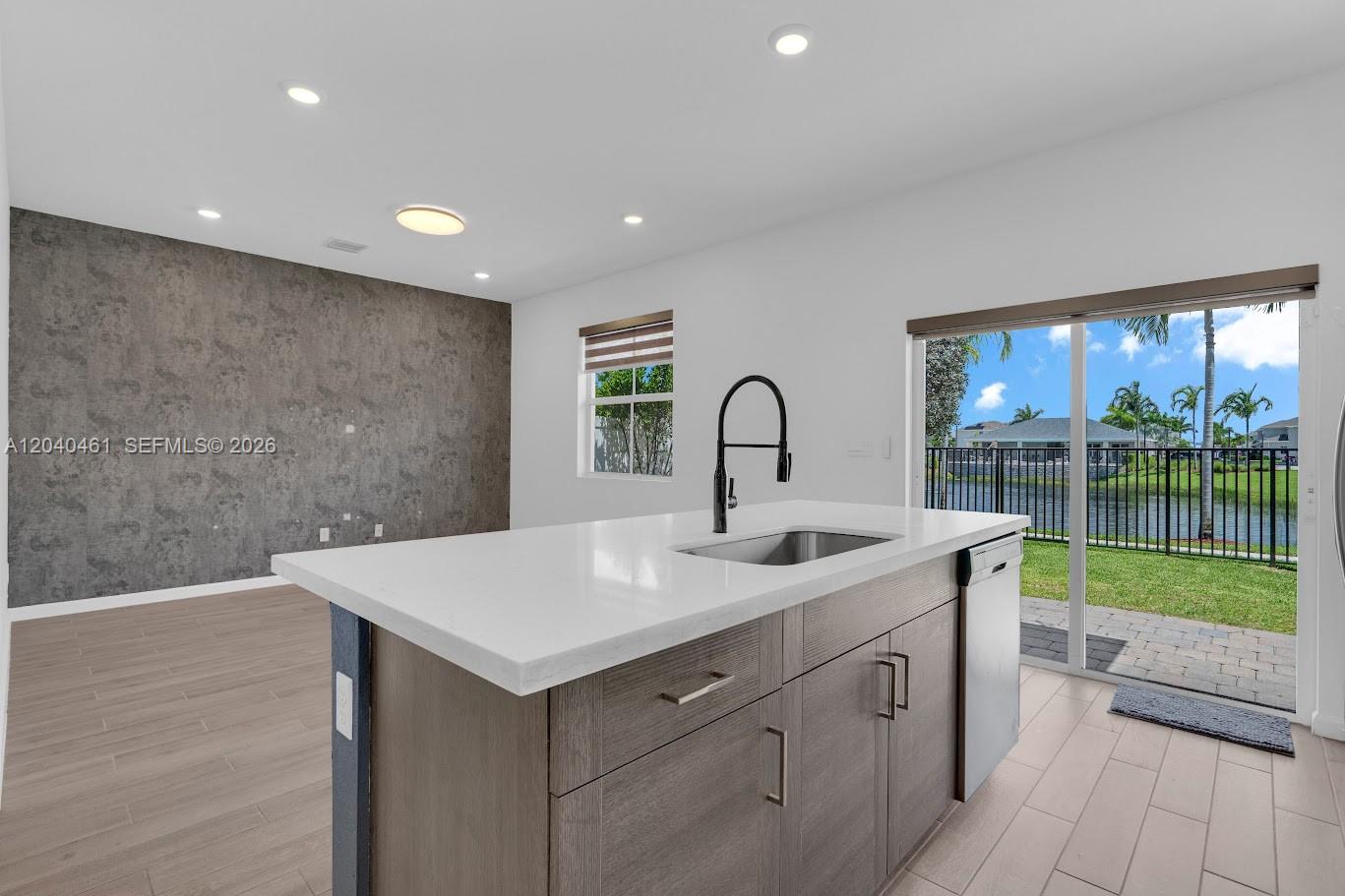A kitchen island with a sink sits before a sliding glass door overlooking a lake — 805 SE 18th St, Homestead FL 33034, HOMESTEAD, FL