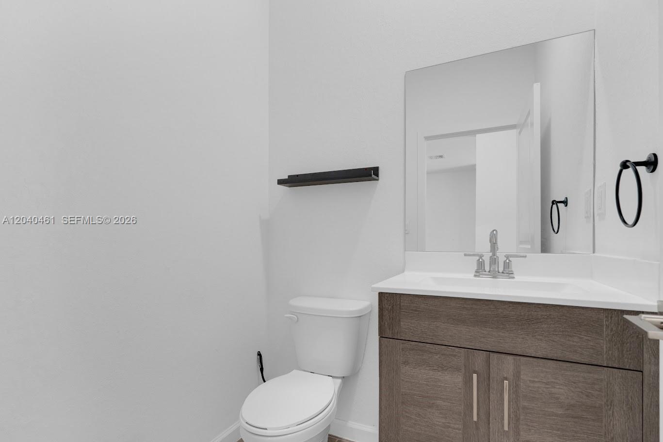 A bathroom features a wood vanity with a white countertop, a mirror, and a toilet — 805 SE 18th St, Homestead FL 33034, HOMESTEAD, FL