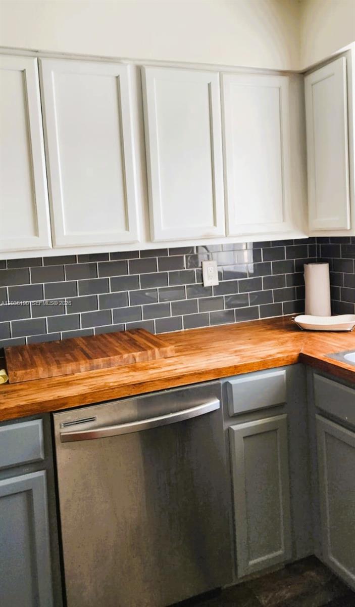 A kitchen features white upper cabinets, gray lower cabinets, a wood countertop, and gray subway tile — 2784 E Dudley Dr E, West Palm Beach FL 33415, WEST PALM BEACH, FL