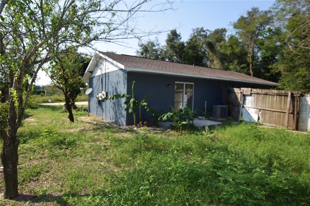 The exterior of a blue house features a sliding glass door and a wooden fence — 911 NW 59TH COURT, OCALA, FL