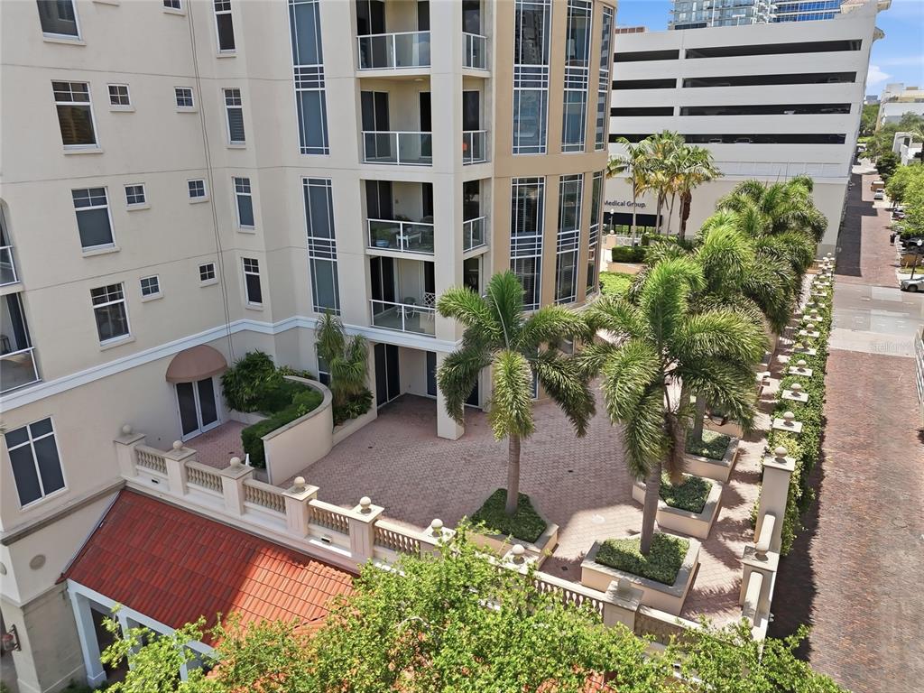 An elevated view shows a paved courtyard with palm trees beside a multi-story apartment building — 100 BEACH DRIVE NE UNIT 301, ST PETERSBURG, FL