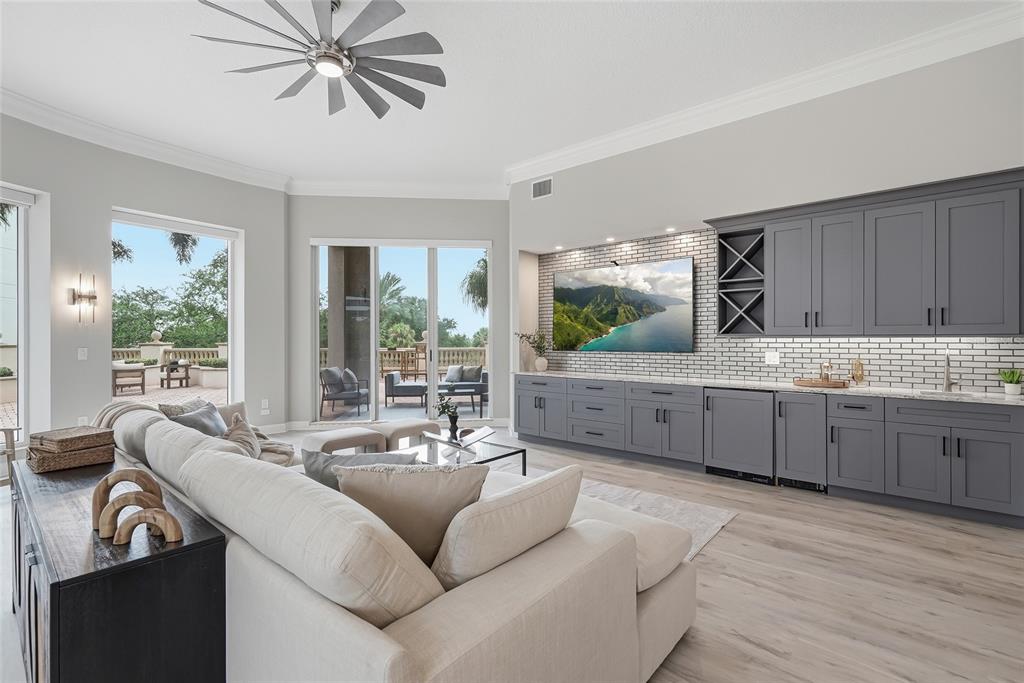 A living room features a large sectional sofa, gray cabinetry, a television, and sliding glass doors — 100 BEACH DRIVE NE UNIT 301, ST PETERSBURG, FL