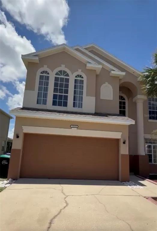 A two-story house with a beige stucco exterior, a two-car garage, and a concrete driveway — 13406 MEADOW BAY LOOP, ORLANDO, FL