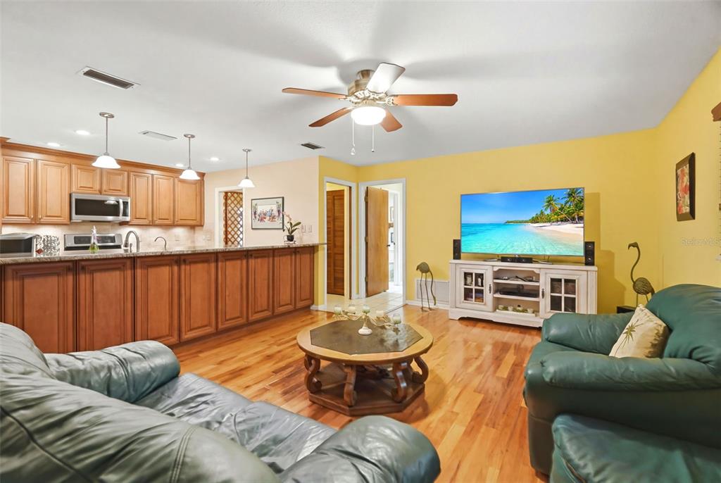 A living room with hardwood floors, a kitchen island, and a television on a stand — 1660 NARNIA COURT, DUNEDIN, FL