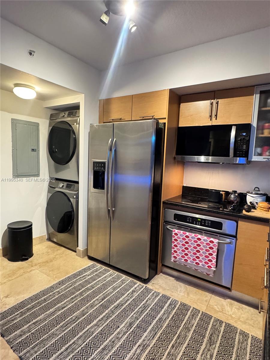 A kitchen features stainless steel appliances, light wood cabinetry, and a stacked washer and dryer — 31 SE 5th St # 1402, Miami FL 33131, MIAMI, FL