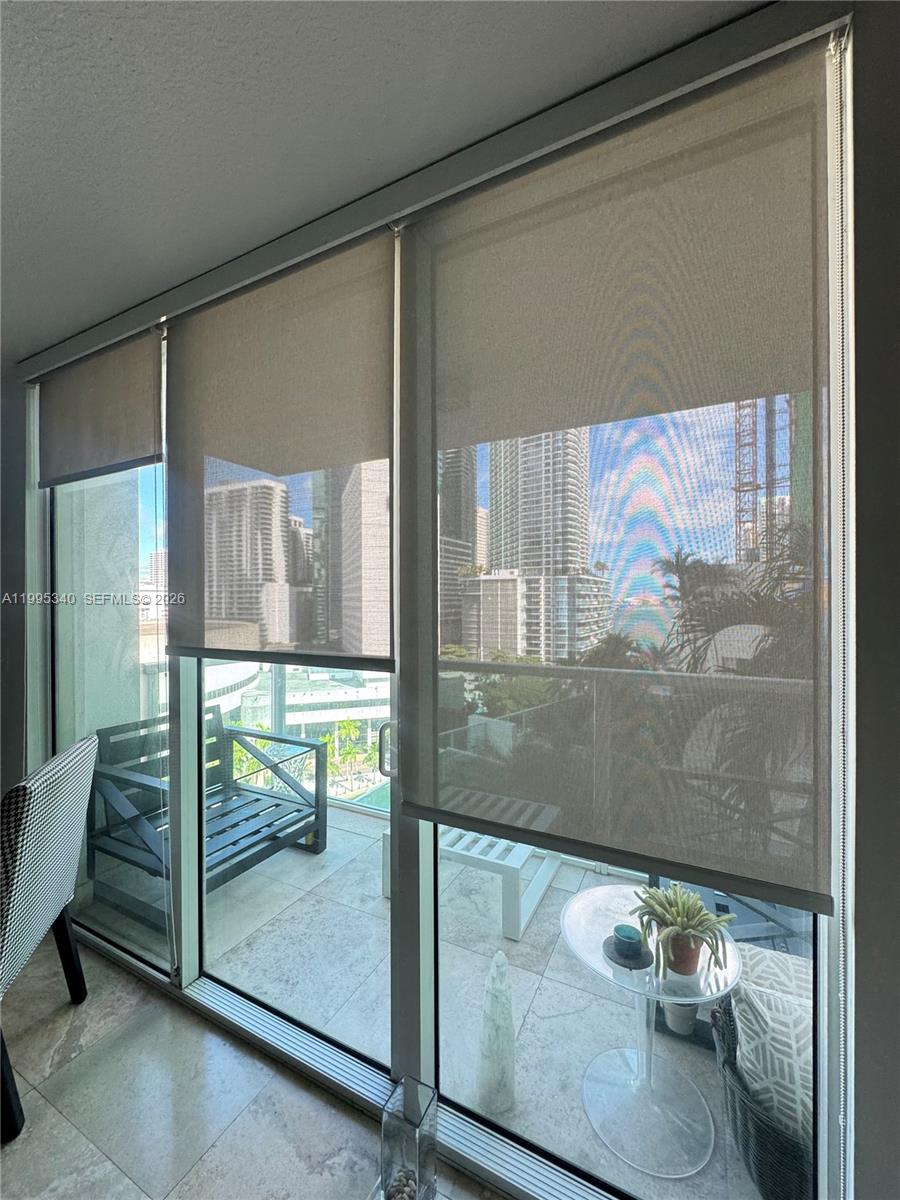 A room with floor-to-ceiling windows and roller shades overlooking a city balcony — 31 SE 5th St # 1402, Miami FL 33131, MIAMI, FL
