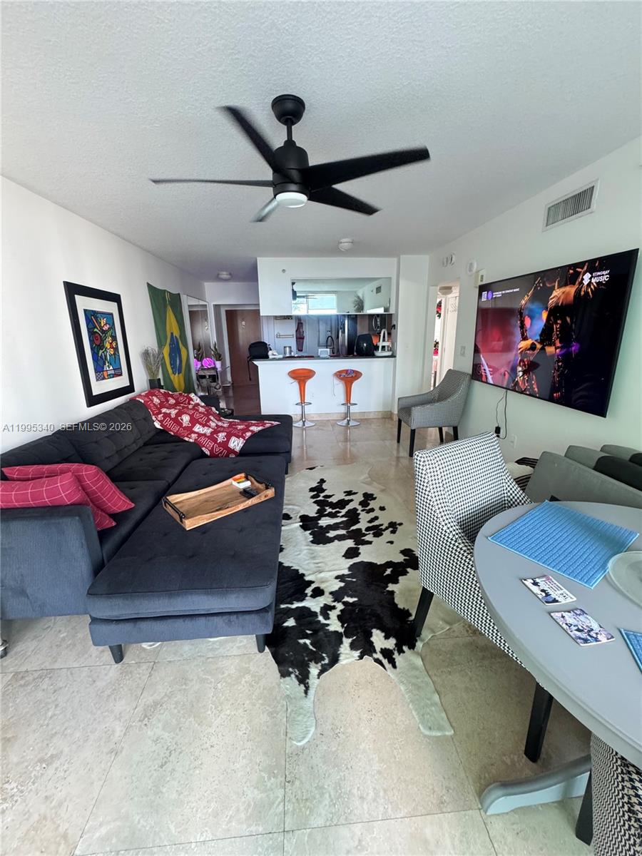 A living room features a sectional sofa, a cowhide rug, and a wall-mounted television — 31 SE 5th St # 1402, Miami FL 33131, MIAMI, FL