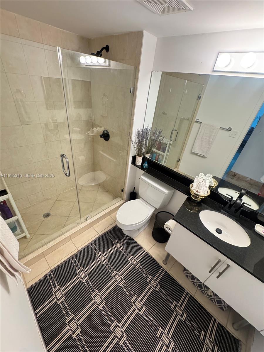 A bathroom features a glass-enclosed shower, a white toilet, and a black vanity countertop — 31 SE 5th St # 1402, Miami FL 33131, MIAMI, FL