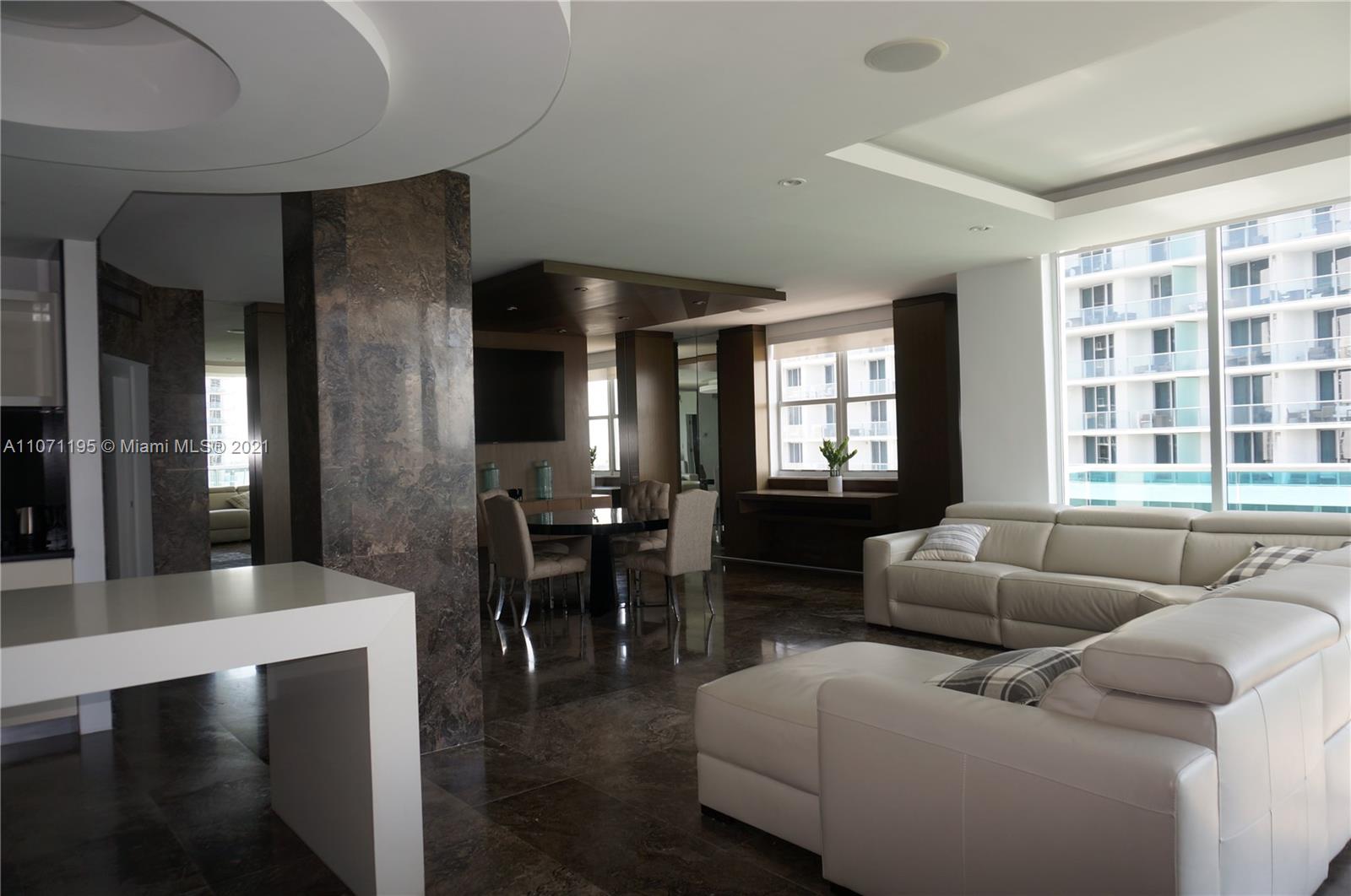 A modern living and dining area features dark marble floors, a white sectional, and stone columns — 4001 S Ocean Dr, Hollywood FL 33019, HOLLYWOOD, FL