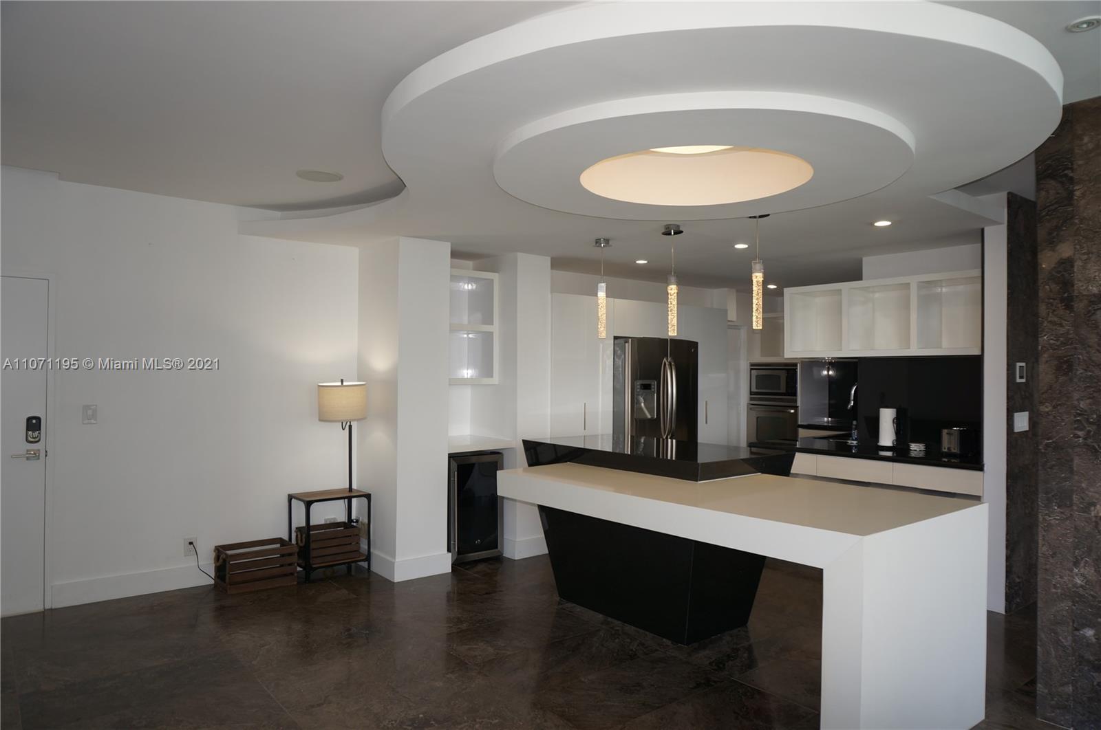 A modern kitchen features a two-tiered island, white cabinetry, and a circular recessed ceiling design — 4001 S Ocean Dr, Hollywood FL 33019, HOLLYWOOD, FL