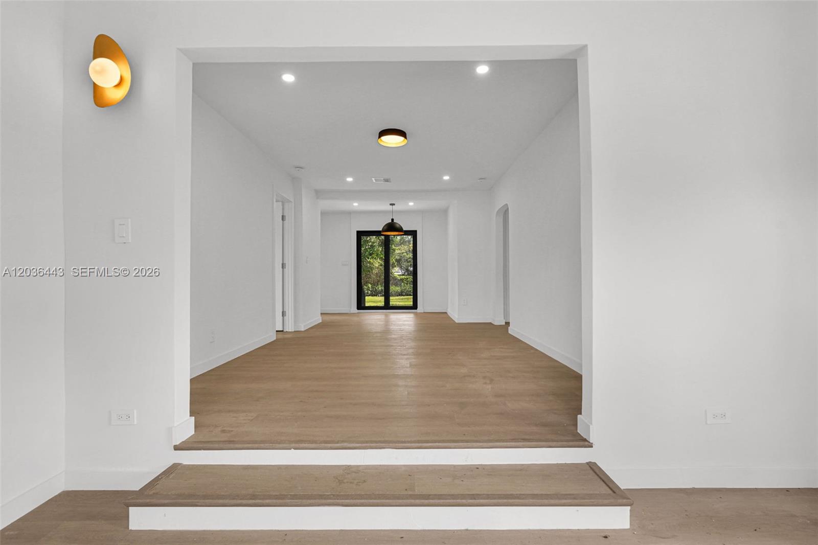 A sunken living area features light wood flooring, white walls, and a rear glass door — 81 NW 45th St # 0, Miami FL 33127, MIAMI, FL