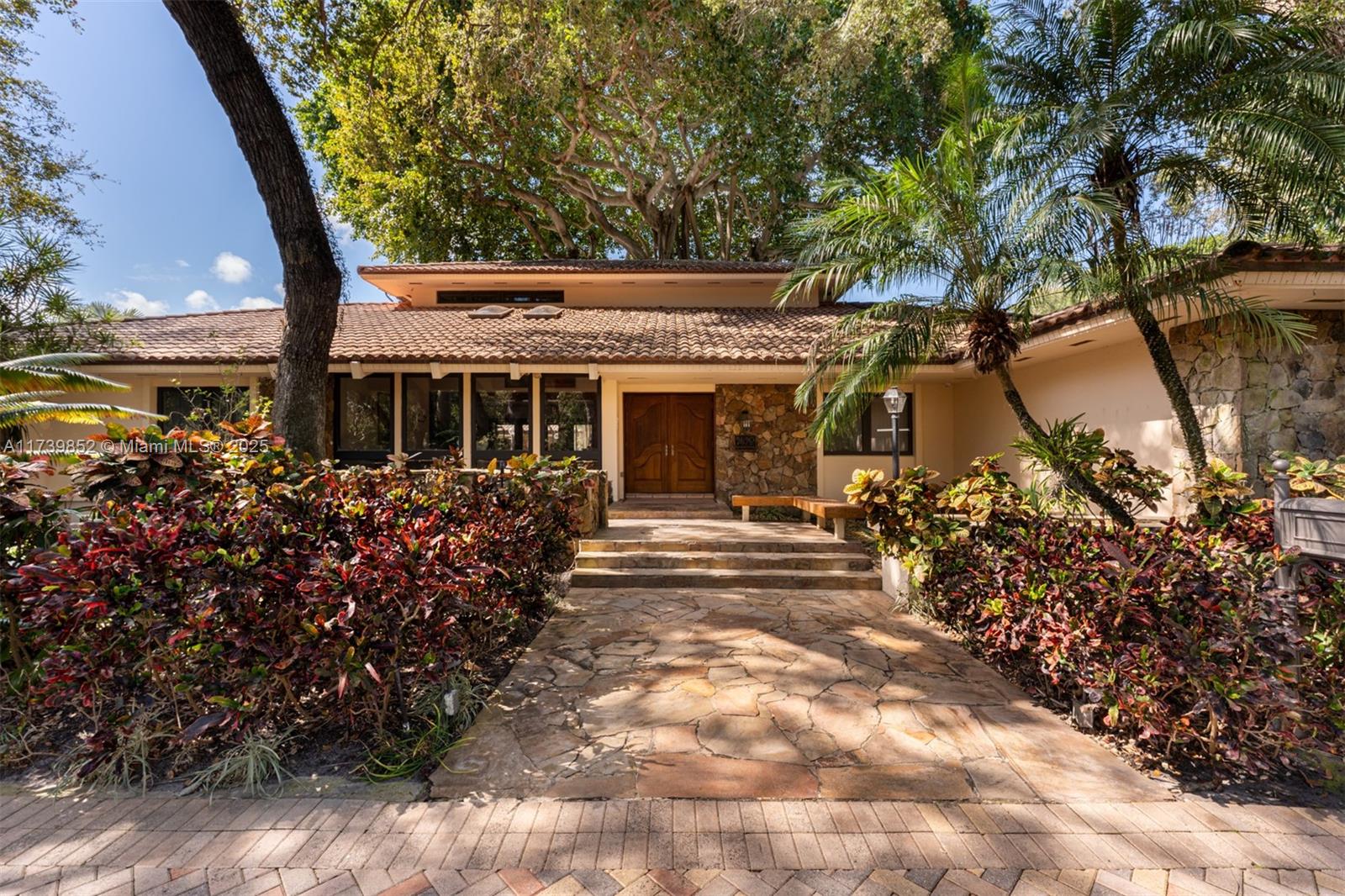A stone walkway leads to the entrance of a single-story house with a tiled roof — 9490 Old Cutler Ln, Coral Gables FL 33156, CORAL GABLES, FL