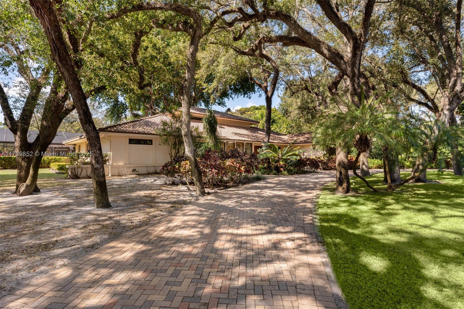 A paved driveway leads to a single-story house surrounded by large, mature trees — 9490 Old Cutler Ln, Coral Gables FL 33156, CORAL GABLES, FL