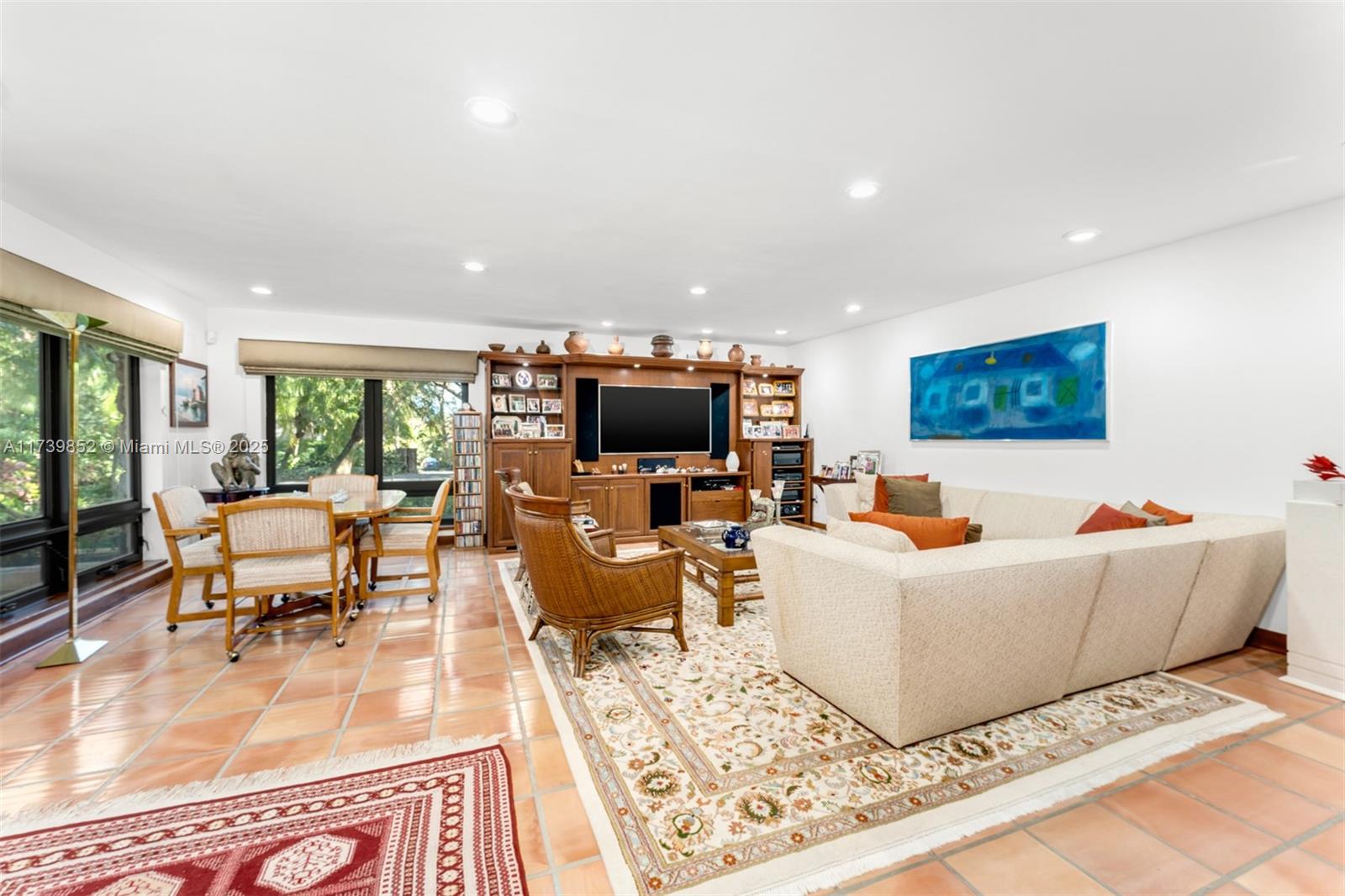 A living room with tile floors, a large sectional sofa, and a wooden entertainment center — 9490 Old Cutler Ln, Coral Gables FL 33156, CORAL GABLES, FL