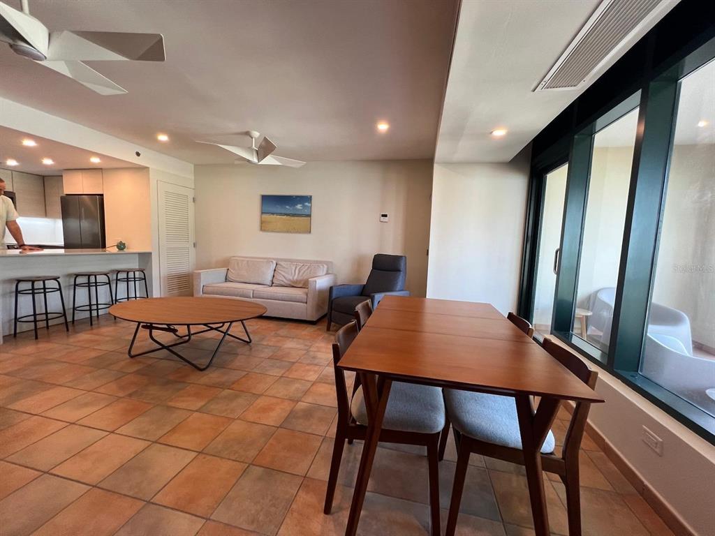 An open-concept living and dining area features tile flooring, a kitchen island, and large windows — OCEAN VILLAS I 6000 BLVD. RIO MAR UNIT /, RIO GRANDE, PR