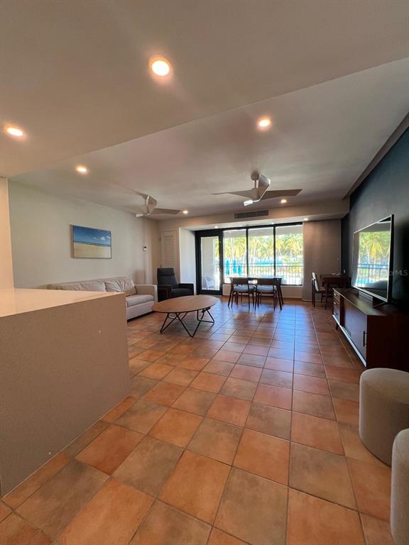 An open-concept living and dining area features tile flooring, a balcony, and a flat-screen television — OCEAN VILLAS I 6000 BLVD. RIO MAR UNIT /, RIO GRANDE, PR
