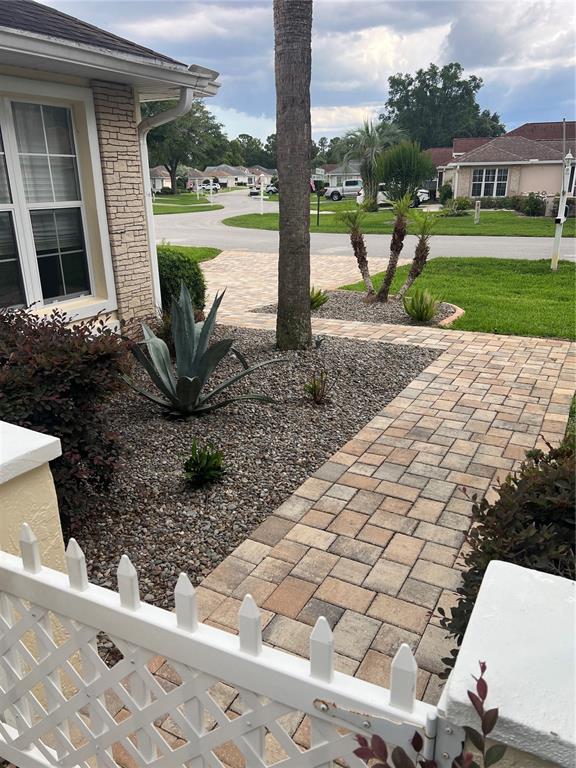 A paved walkway leads to a house entrance with a gravel garden and palm trees — 6847 SW 114TH STREET ROAD, OCALA, FL
