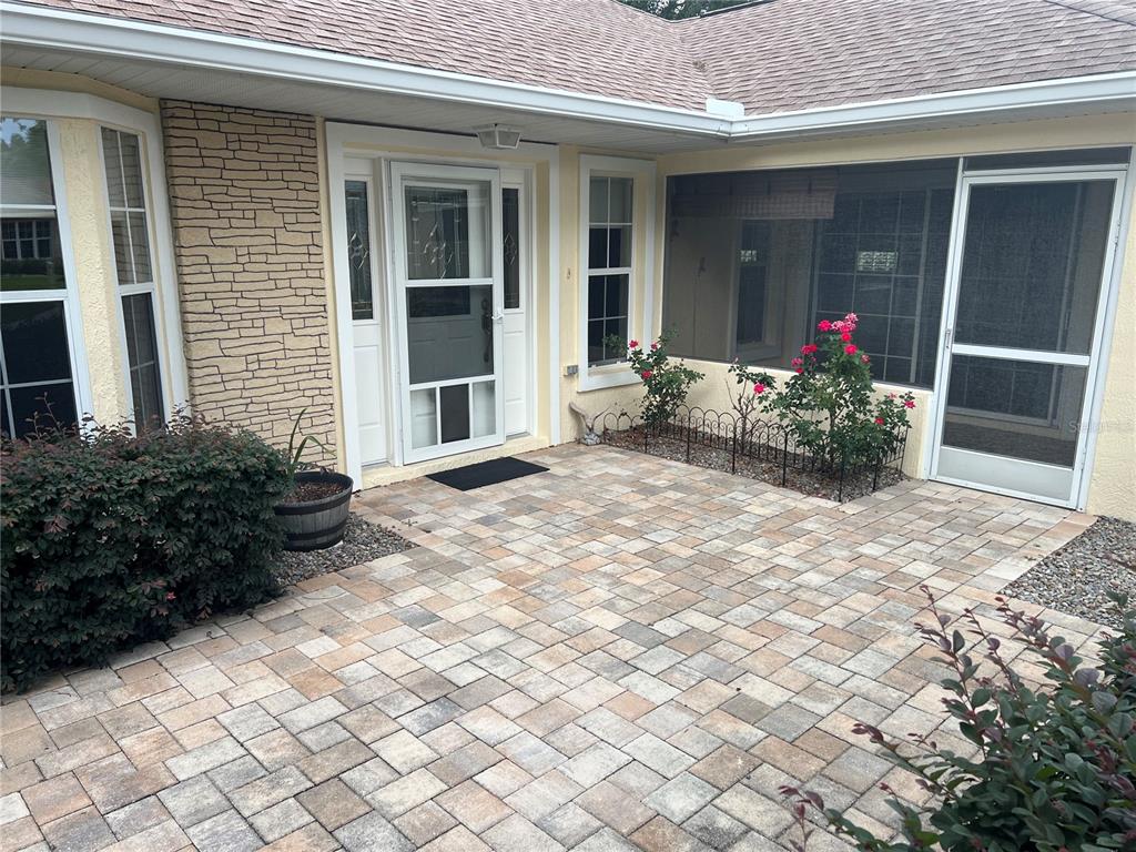 A stone-paved patio sits in front of a house with a screened porch and entryway — 6847 SW 114TH STREET ROAD, OCALA, FL