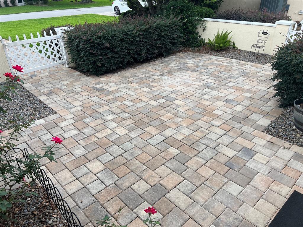 A paved patio area features a herringbone pattern, a white lattice gate, and landscaping — 6847 SW 114TH STREET ROAD, OCALA, FL