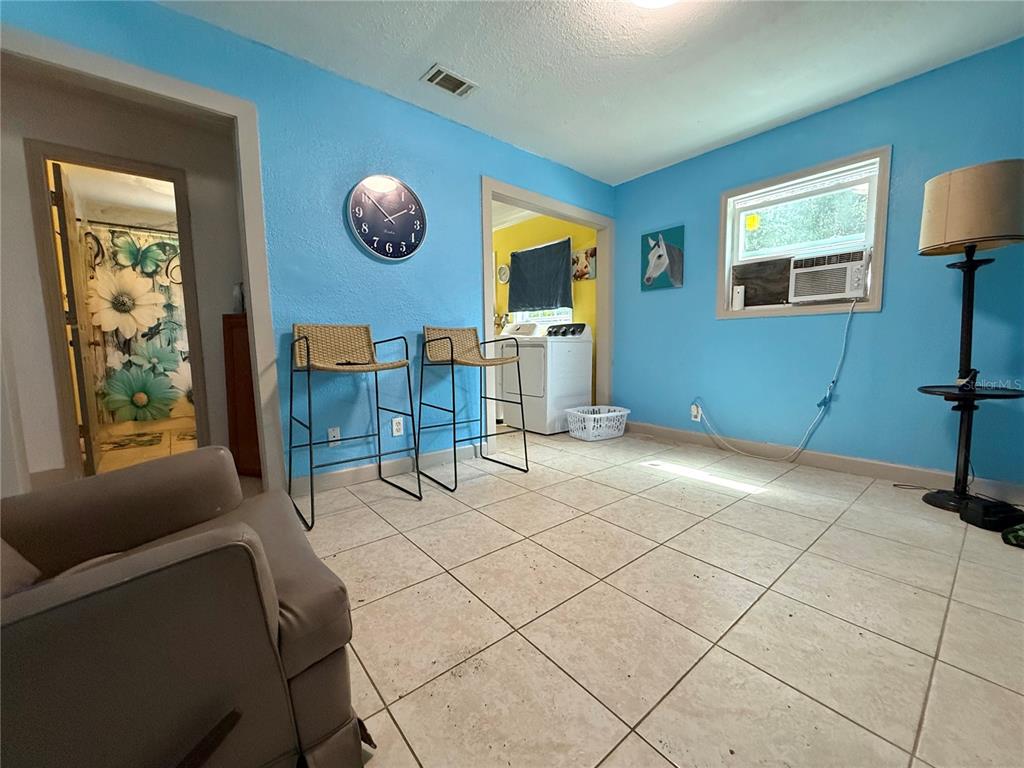 A room with light blue walls, tile flooring, two bar stools, and a wall clock — 6415 NE 23RD AVENUE, OCALA, FL