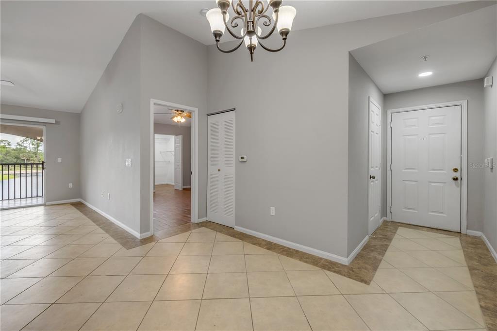 An entryway with light tile flooring, a white front door, and a chandelier — 940 VILLAGE TRAIL UNIT 4-306, PORT ORANGE, FL