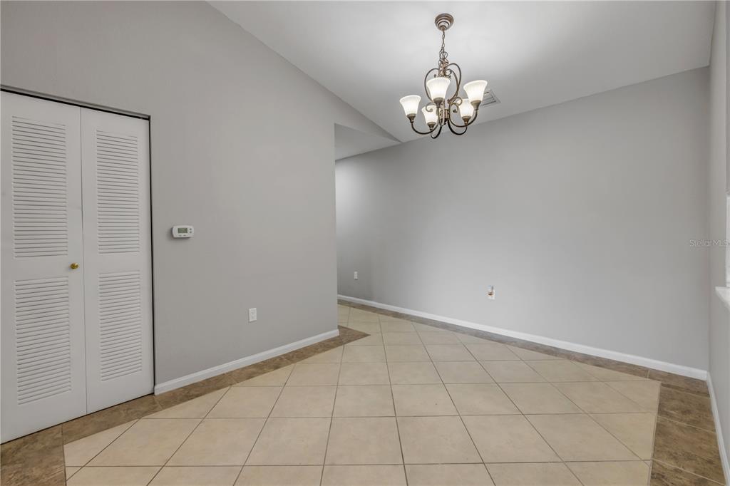A dining area features light gray walls, a chandelier, and a tiled floor with a border — 940 VILLAGE TRAIL UNIT 4-306, PORT ORANGE, FL